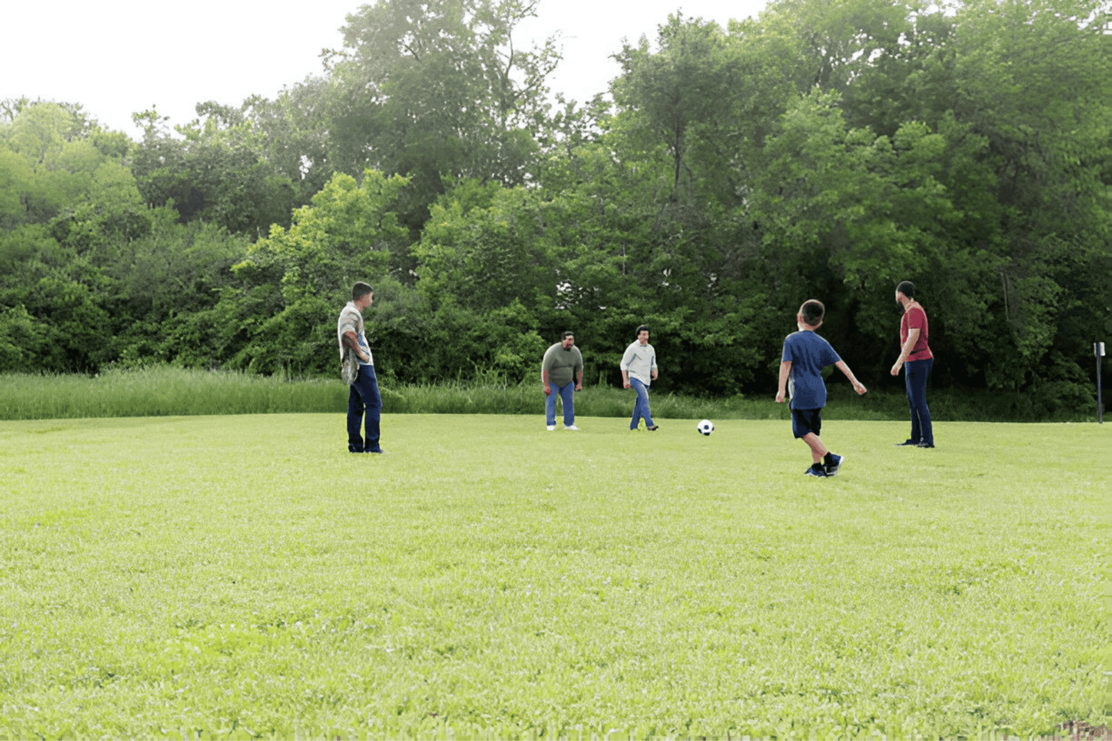 Family Reunion Games-Male family members play soccer together in a field during a family reunion