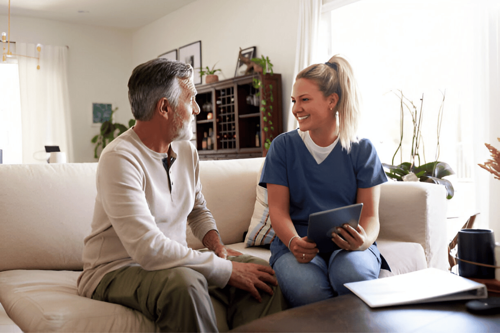 USA Home Health Services -Female healthcare worker using a tablet computer with a senior Hispanic man during a home visit